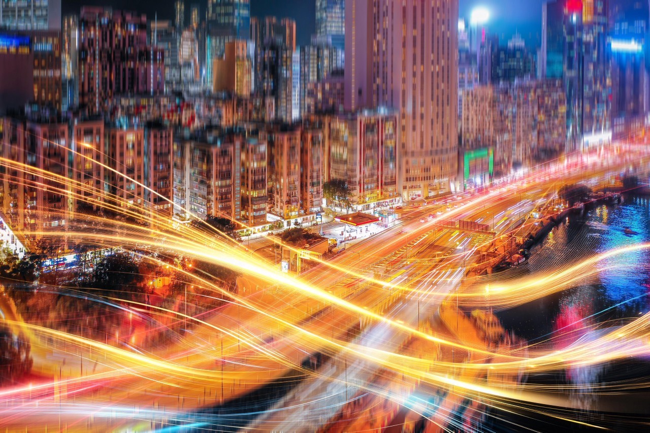 Paisagem urbana com luzes brilhantes à noite. Rastros de luz fluem pelo ar, criando uma sensação de movimento - Foto: Yiu Cheung / Getty Images